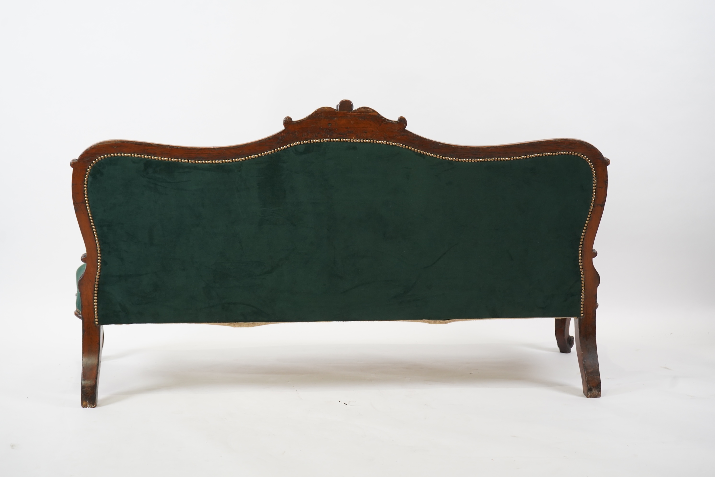 A pair of Victorian carved oak settees, recently re-upholstered in deep buttoned green velvet, the scroll carved crest rails over serpentine seats on cabriole front legs, 160cm wide, 96cm high, Provenance - previously gi